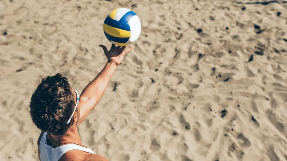 mężczyzna podbijający piłkę do siatkówki na plażowym boisku