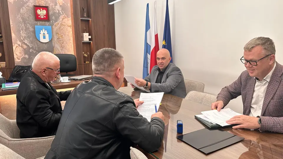 4 osoby siedzące przy biurku w gabinecie Wójta.
